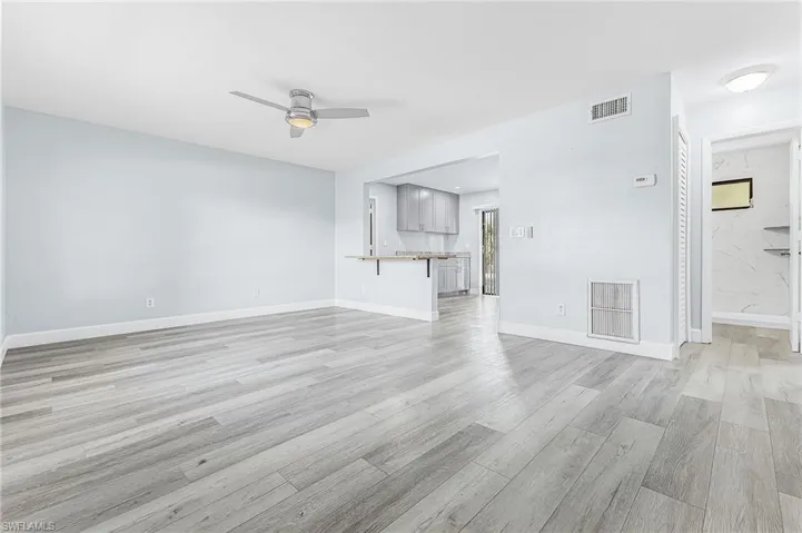 Open concept living space featuring wood-finish flooring, light-toned walls, and a contemporary ceiling fan