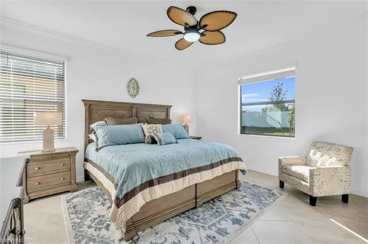 Neutral-toned tile flooring, large windows with natural light, and a central ceiling fan with palm-leaf style blades
