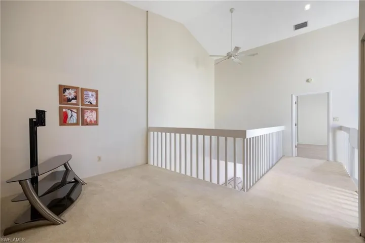Hallway with carpet floors and high vaulted ceiling