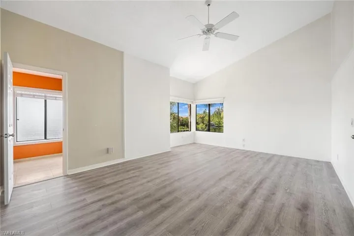 Unfurnished room featuring hardwood / wood-style floors, high vaulted ceiling, and ceiling fan
