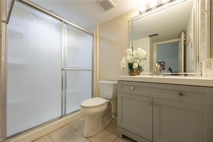 Bathroom with walk in shower, tile patterned floors, toilet, and vanity