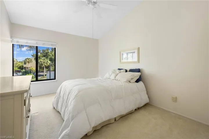 Bedroom featuring vaulted ceiling, light colored carpet, and ceiling fan