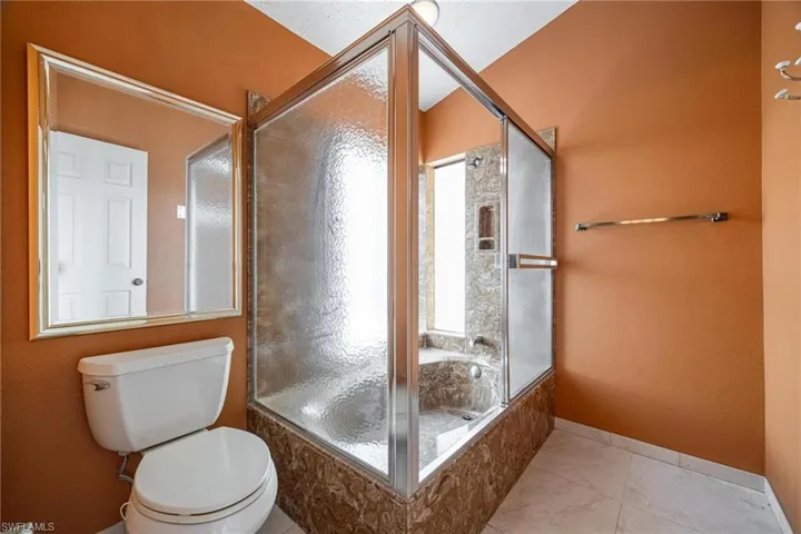 Bathroom with a healthy amount of sunlight, toilet, and tile patterned floors