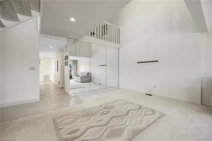 Living room with a high ceiling and light carpet