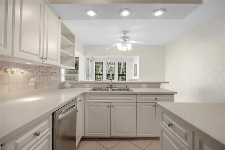 Kitchen with ceiling fan, sink, dishwasher, light tile patterned floors, and backsplash