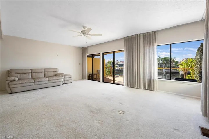 Unfurnished living room with ceiling fan, carpet, and plenty of natural light