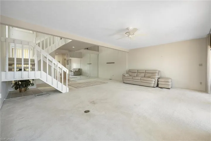 Unfurnished living room featuring carpet and ceiling fan