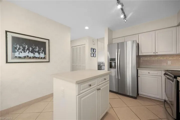 Kitchen featuring light tile patterned flooring, tasteful backsplash, white cabinets, stainless steel appliances, and track lighting