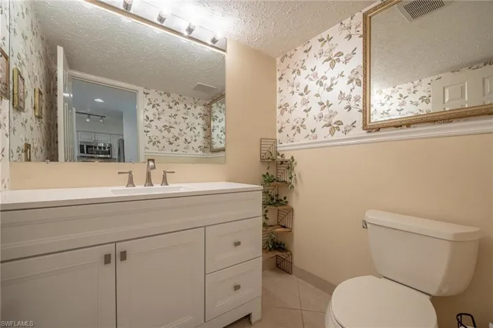 Bathroom featuring vanity, tile patterned floors, a textured ceiling, and toilet