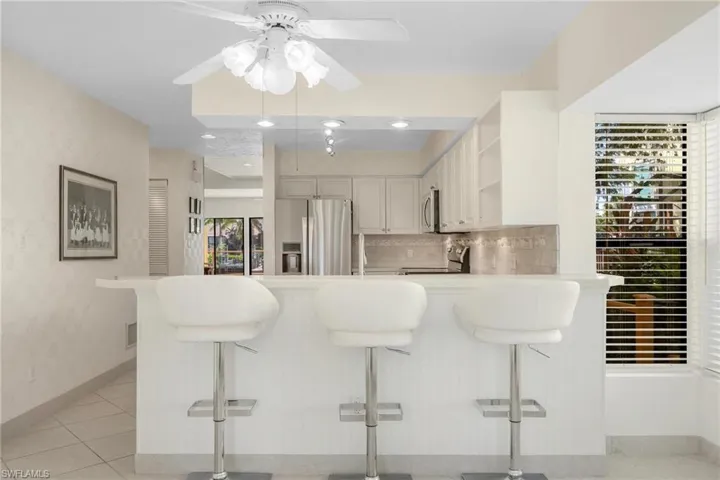 Kitchen featuring kitchen peninsula, tasteful backsplash, a kitchen breakfast bar, and stainless steel appliances