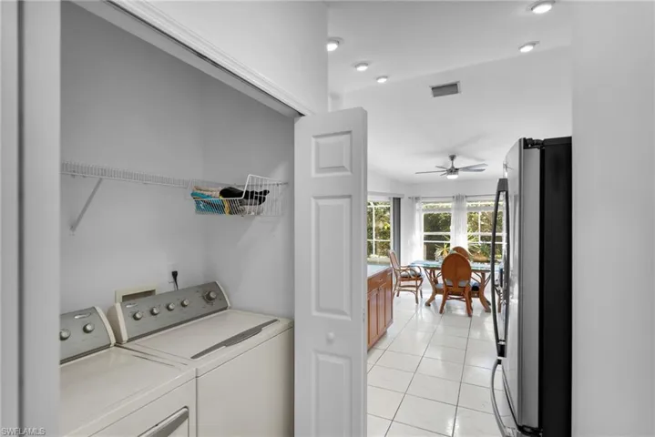 Washroom featuring washer and dryer, a ceiling fan, and light tile patterned flooring