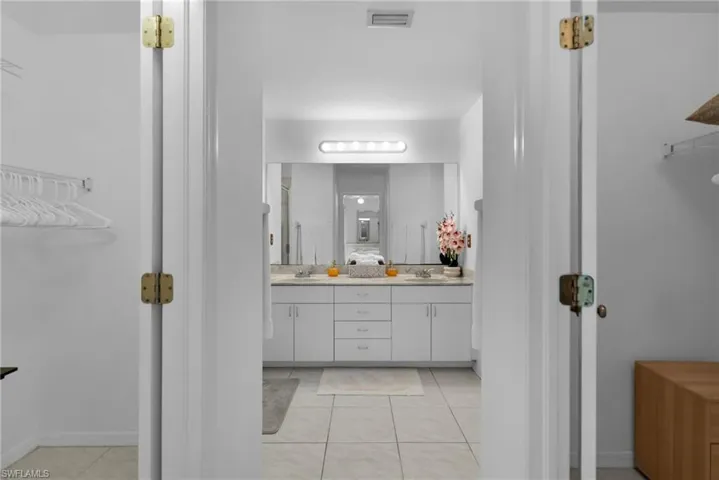 Bathroom with double vanity, tile patterned flooring, and baseboards