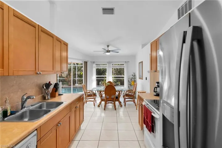 Kitchen with white appliances, a sink, light tile patterned flooring, a ceiling fan, and light countertops