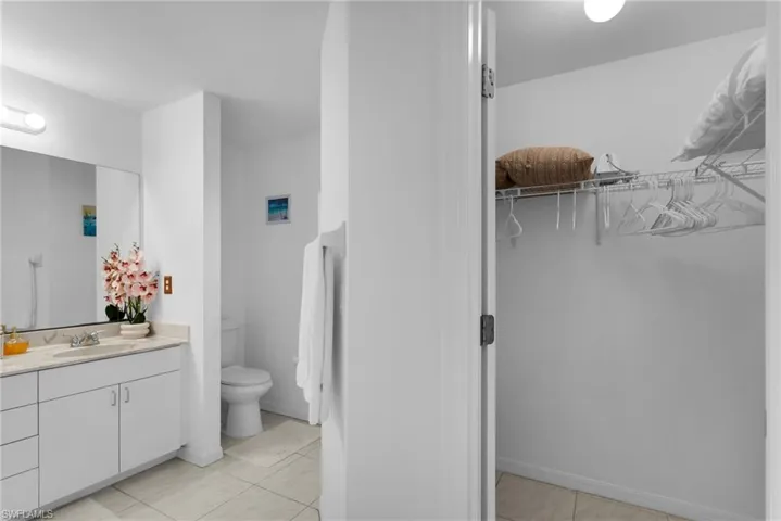 Bathroom with vanity, toilet, a walk in closet, and tile patterned floors