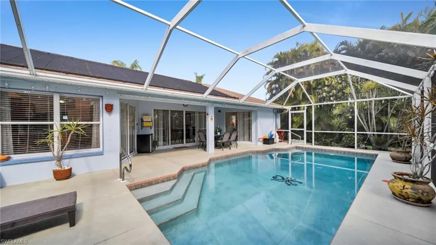 Screened-in swimming pool featuring integrated steps, a concrete deck, and a full enclosure