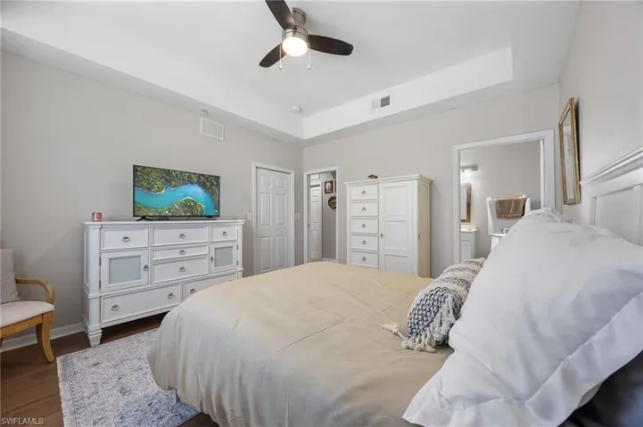 Bedroom featuring a tray ceiling, dark wood-style floors, ceiling fan, and a closet