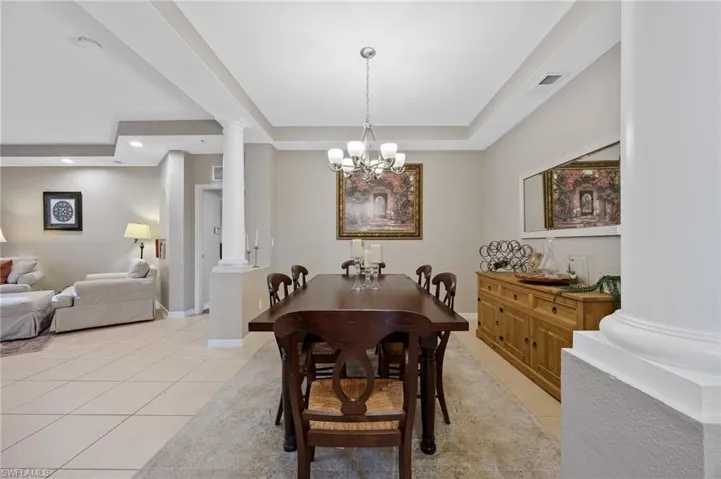 Dining space featuring ornate columns, light tile patterned flooring, a chandelier, and recessed lighting