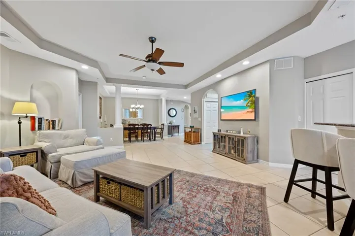 Living area with a tray ceiling, light tile patterned floors, a chandelier, a ceiling fan, and recessed lighting