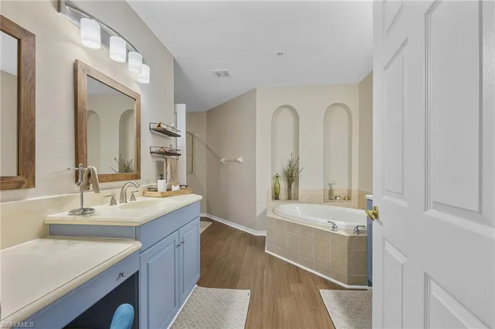 Bathroom with a bath, vanity, and dark wood-type flooring