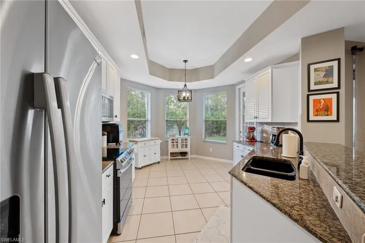 Kitchen with appliances with stainless steel finishes, white cabinetry, dark stone countertops, recessed lighting, and hanging light fixtures