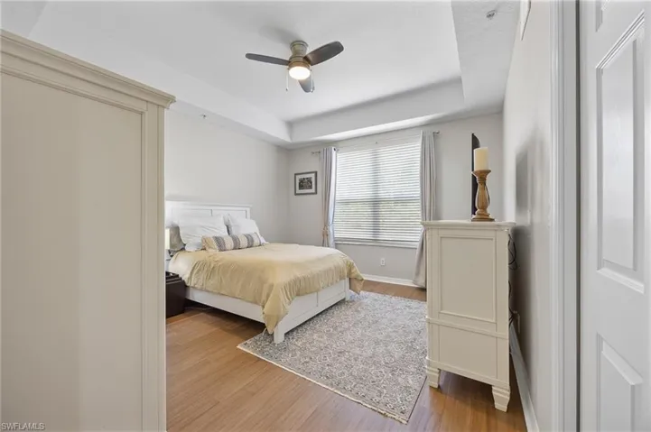 Bedroom featuring a raised ceiling, wood finished floors, and ceiling fan