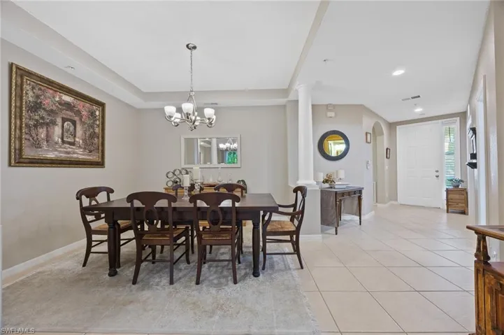 Dining space with light tile patterned floors, arched walkways, recessed lighting, and a chandelier