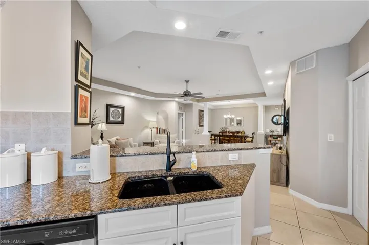 Kitchen featuring a peninsula, dark stone countertops, white cabinetry, recessed lighting, and open floor plan