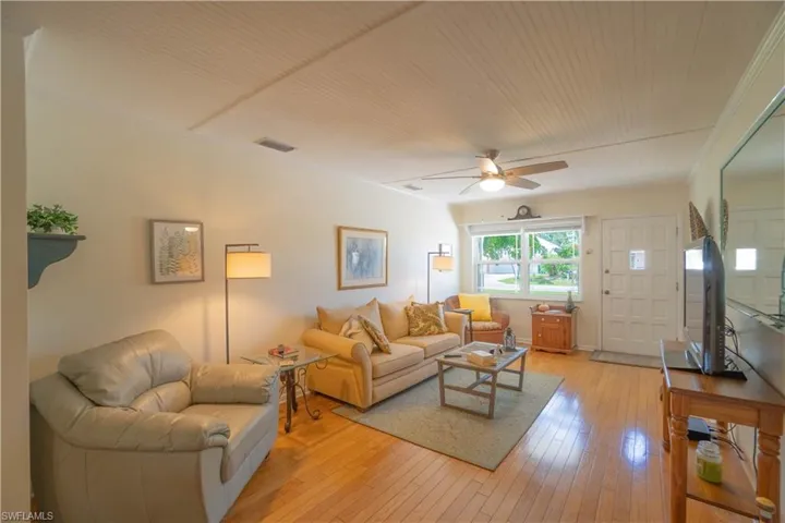 Living area with light wood-style flooring, crown molding, and a ceiling fan