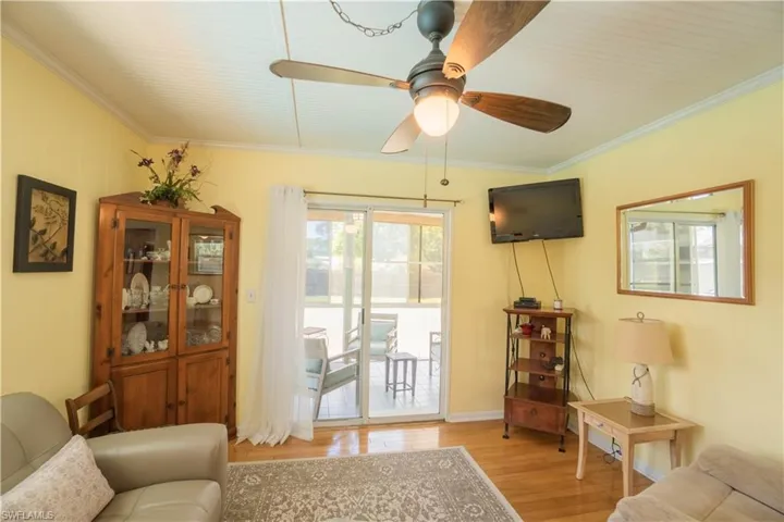 Living area featuring ornamental molding, light wood finished floors, and a ceiling fan