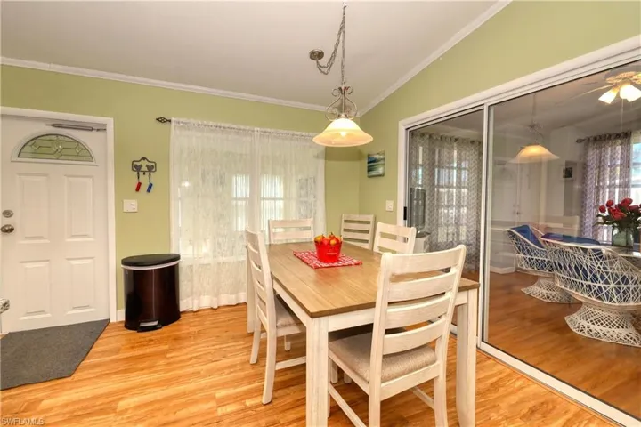 Dining room with lofted ceiling, light wood-type flooring, and crown molding