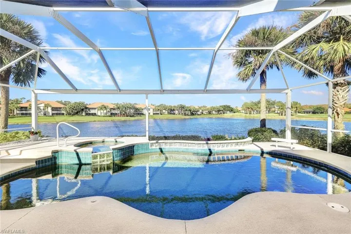 View of pool with an in ground hot tub, a water view, and a lanai