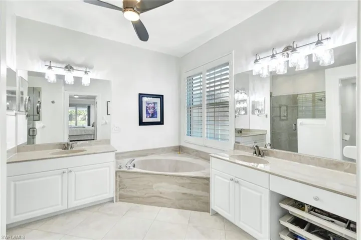 Bathroom featuring ceiling fan, tile patterned flooring, vanity, and shower with separate bathtub