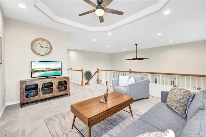 Living room with a tray ceiling, ceiling fan, and crown molding