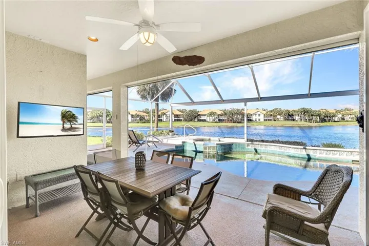Sunroom / solarium with a water view, ceiling fan, and a swimming pool