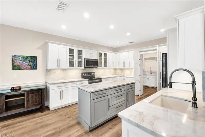 Kitchen featuring light stone countertops, appliances with stainless steel finishes, sink, light hardwood / wood-style flooring, and white cabinets