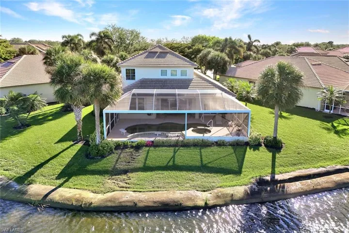 Rear view of house featuring a yard, a water view, and glass enclosure