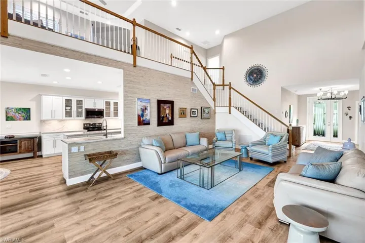 Living room featuring an inviting chandelier, light wood-type flooring, a towering ceiling, and french doors