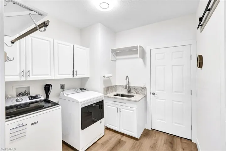 Washroom featuring cabinets, sink, a barn door, separate washer and dryer, and light hardwood / wood-style floors