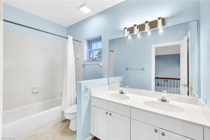 Full bathroom with tile patterned flooring, shower / bath combination with curtain, toilet, and vanity