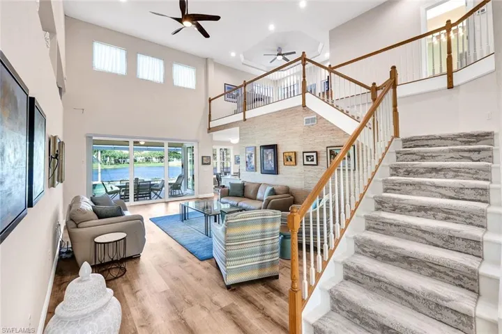 Living room with a towering ceiling, a water view, ceiling fan, and hardwood / wood-style flooring