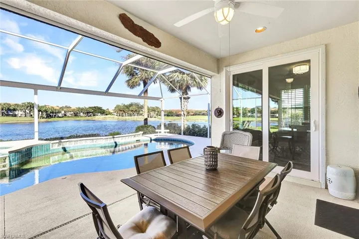 View of patio with a water view, ceiling fan, and a lanai