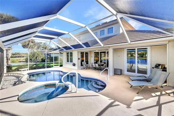 View of swimming pool featuring glass enclosure, an in ground hot tub, and a patio