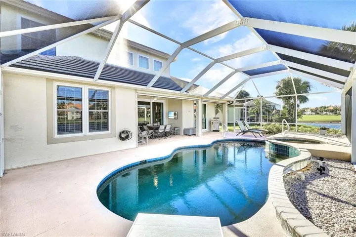 View of swimming pool featuring glass enclosure, an in ground hot tub, and a patio