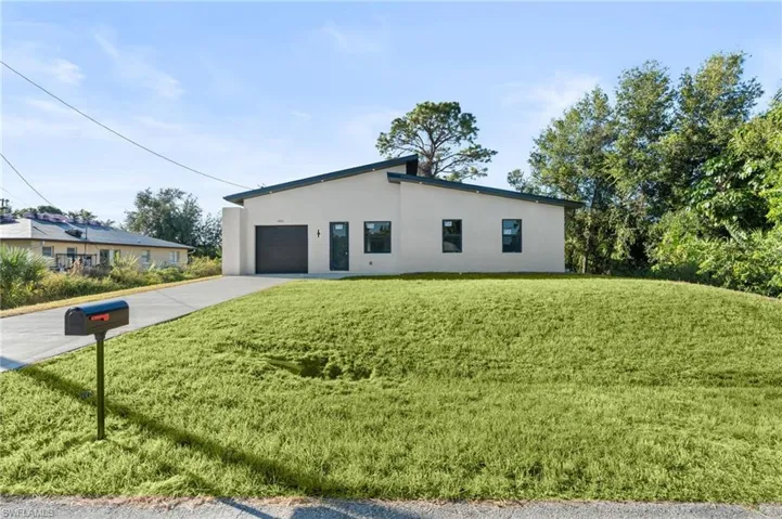 View of side of property featuring driveway, stucco siding, a yard, and a garage