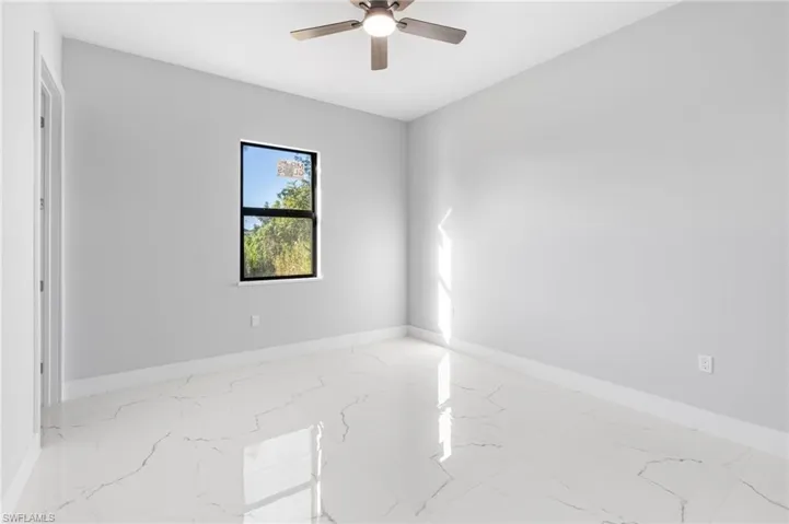 Spare room featuring light marble finish floors and ceiling fan
