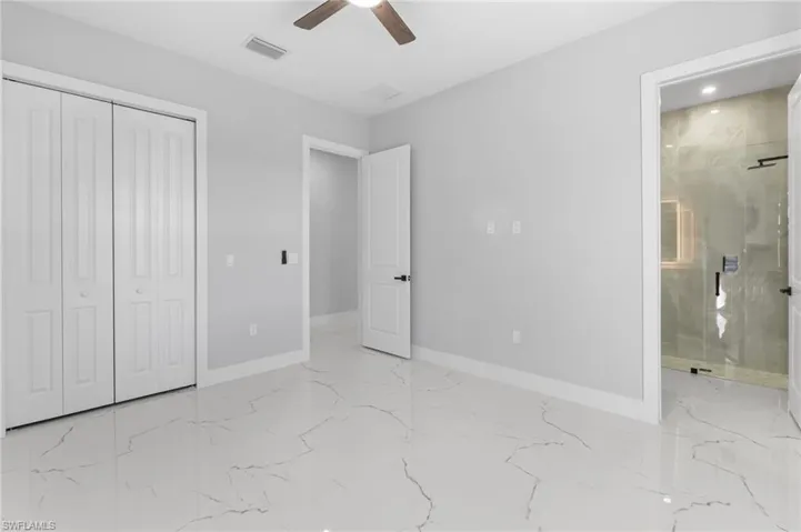 Unfurnished bedroom with light marble finish flooring, a closet, and a ceiling fan