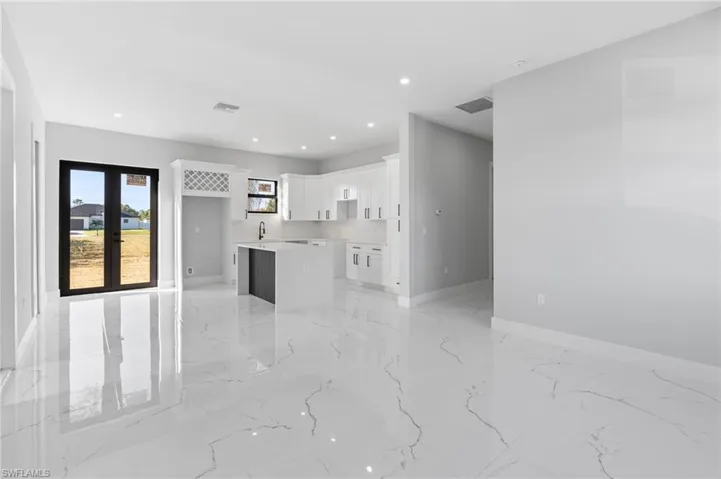 Unfurnished living room featuring recessed lighting, light marble finish flooring, and french doors