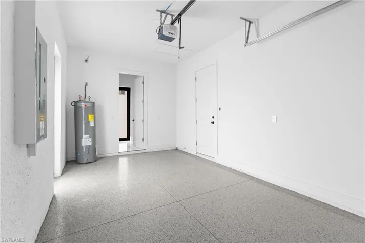 Garage featuring electric water heater and a garage door opener