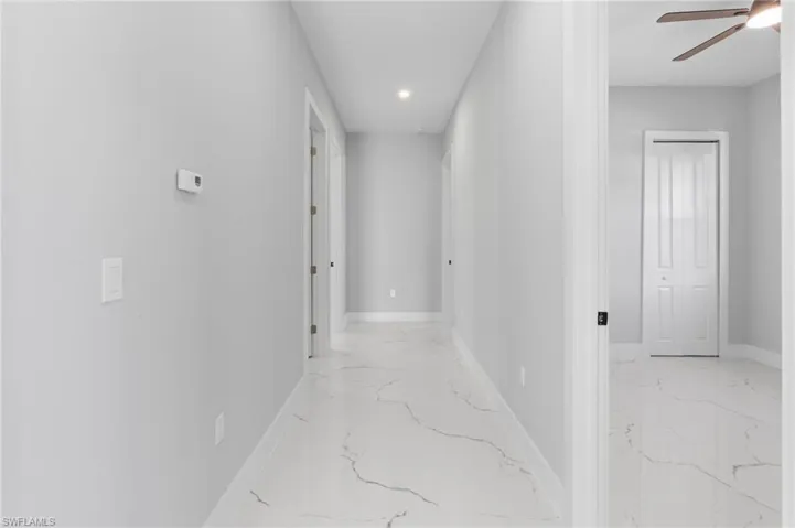 Hallway featuring recessed lighting and light marble finish floors