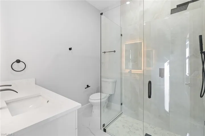 Bathroom featuring vanity, a stall shower, and marble finish flooring